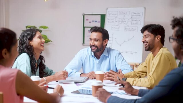 Group of Team members or colleagues spending time together by laughing and talking together after work at office - concept of friendship, team building and enjoyment