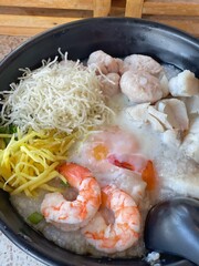 boiled rice clear soup with shrimp in a ceramic bowl on wooden table. homemade style food concept.