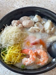 boiled rice clear soup with shrimp in a ceramic bowl on wooden table. homemade style food concept.