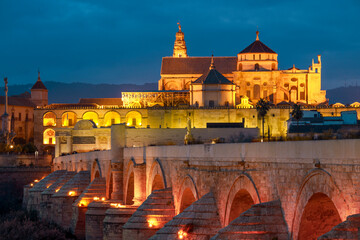 View of the Roman bridge over the Guadalquivir river and the mosque and cathedral in Cordoba, Andalusia, Spain with artificial colorfu light at night