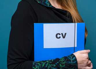 Dziewczyna trzyma w rękach teczkę z napisem CV, rozmowa kwalifikacyjna - obrazy, fototapety, plakaty