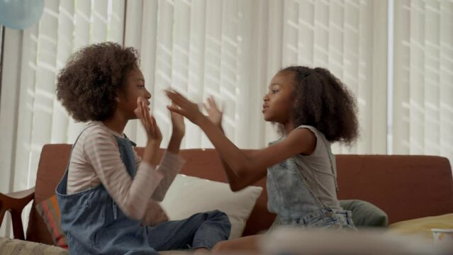 Cute girls sitting on sofa playing clapping game