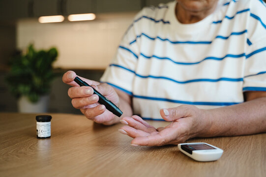 Senior woman puncturing finger for blood sugar test at home