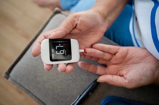 Hands of woman using glucometer at home