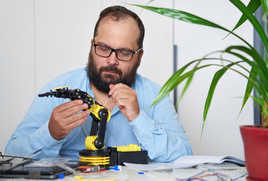 Engineer working on robotic arm at desk in office