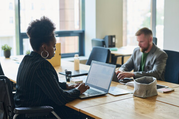 Businesswoman and businessman working on laptop in office
