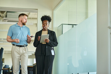 Businesswoman discussing over tablet PC with coworker in office