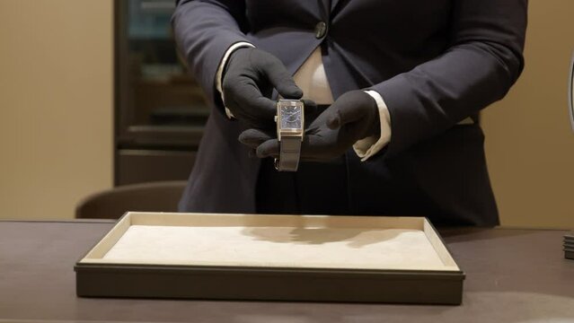 Smart male retailer showing luxury fashionable wristwatch over boutique store counter