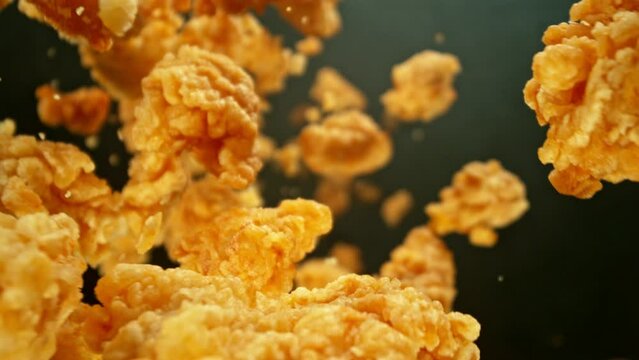 Super Slow Motion of Flying Fried Chicken Piecers on Black Background. Camera Makes Rotation Move. Filmed on High Speed Cinema Camera, 1000fps. Speed Ramp Effect.