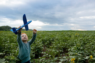 Smiling redhead boy playing with toy airplane in field