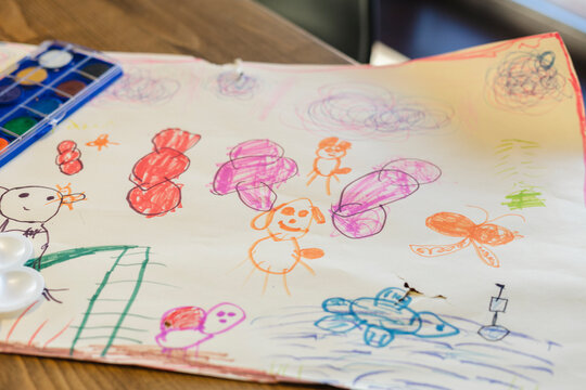 Paper with children drawing on table at home