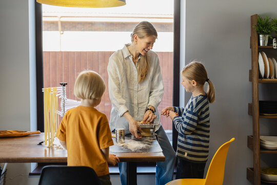 Happy family cutting dough in pasta maker at home