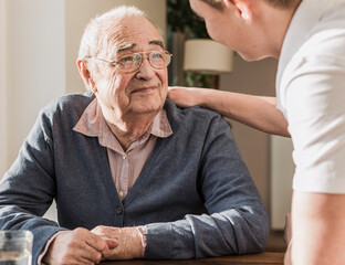 Young man taking care of grandfather at home