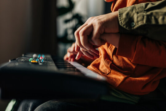Father teaching son to play electric piano at home