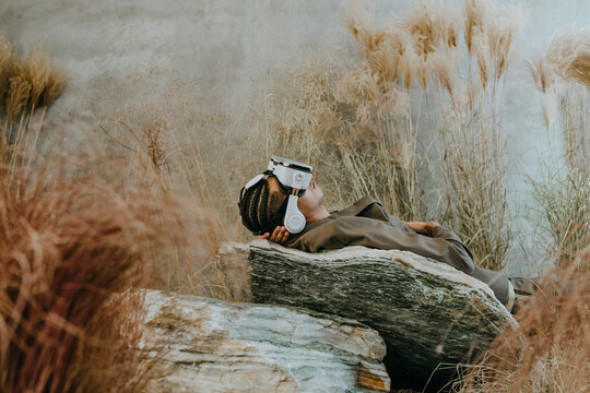 Businessman wearing virtual reality simulator and lying on rock in garden