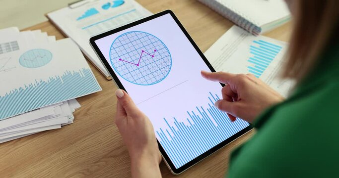 Businesswoman studying charts on digital tablet and flipping through pages closeup 4k movie slow motion