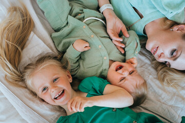 Overjoyed mother and children sharing laughter on a bed, a heartwarming family moment full of...