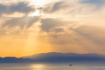 Beautiful fluffy clouds and rays of sunshine painted in dramatic colors at sunset. Golden hour in...