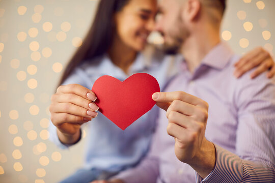 Valentine day emotion. People in love, man and woman holding red heart symbol close up, happy romantic.Loving couple showing romantic affection, male, female pair expression of romance