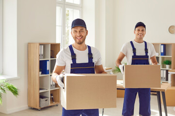 Moving company workers in uniforms take parcels from a modern office. Two happy, cheerful, smiling...