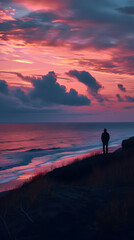 Person standing at the danish west coast with red clouds in the background. 