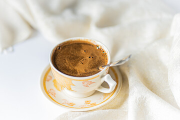 Cup of coffee with chocolate on a light white table and beige napkin. Breakfast coffee in bed