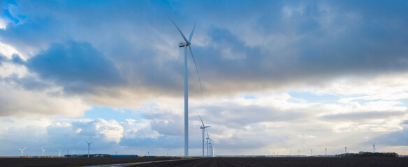 White and grey clouds in a blue sky over wind turbines in winter, Almere, Flevoland, Netherlands, January 1, 2024