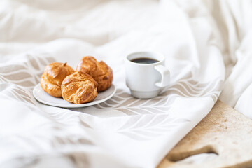 Cup of coffee with cookies on light white table and beige napkin. Breakfast coffee in bed