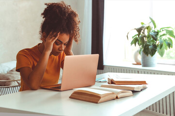 Frustrated African descent young woman in front of laptop at home, receiving e-mail with bad news