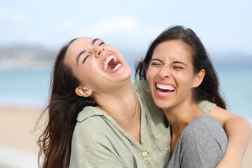 Two joyful friends laughing hilariously on the beach