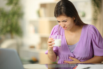 Woman drinking milk suffering belly ache at home - obrazy, fototapety, plakaty