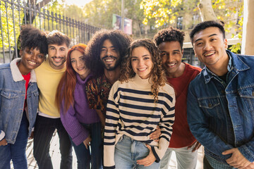portrait of multiracial group of smiling friends looking at camera on city streets - obrazy, fototapety, plakaty