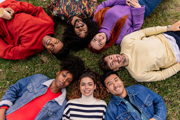 from above group of multicultural friends lying in a circle looking at camera and smiling - obrazy, fototapety, plakaty