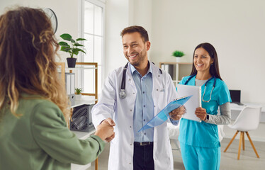 Male doctor with female nurse extend warm handshake to a patient in the hospital. Gesture...