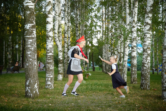 Young and adult schoolgirl on September 1, mother and daughter having fun together. Generations of schoolchildren of USSR and Russia. Female pioneer in red tie and October girl in modern uniform