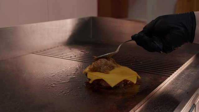 Cooking beef and pork patty for burger. Slow motion grilled burger cutlet with sauce and cheese