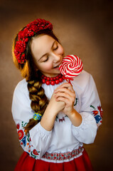 A girl in Ukrainian clothes with a lollipop