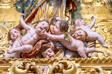 statues of naked children at the feet of Santa Gloria in catholic church