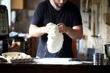 Male hands kneading fresh dough on the kitchen table