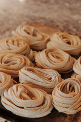 Soft focus of tasty homemade uncooked tagliatelle pasta rolls placed on table in kitchen before boiling