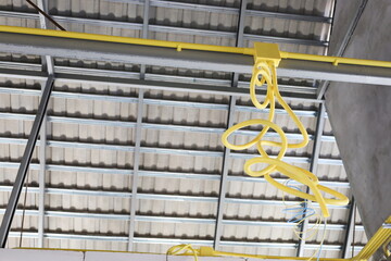 Boxes and electrical conduits on steel frames. Yellow cable conduit hanging from house rafters as...