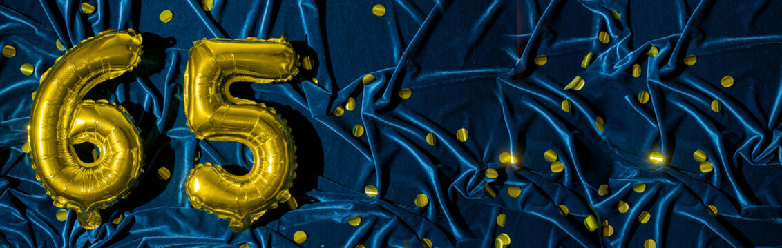 Gold foil balloon number number 65 on a background of blue velvet decoration. Birthday greeting card, inscription sixty-five. Anniversary event. Banner.
