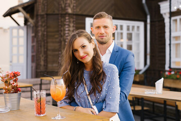 Portrait of a stylish young couple in love in blue flowers in summer in the city at a bar table,...