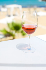 Glass of rose wine against blue water and sea