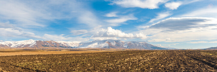 Wide angle panoramic view of Aragats mountains with cultivated field in foreground. Travel destination Armenia