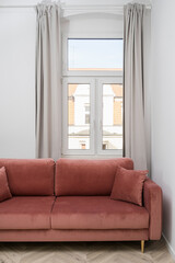 Vertical shot of living room with big window and comfortable red sofa in apartment