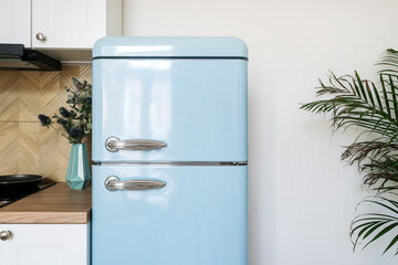 Blue refrigerator with stainless steel handles in retro style in kitchen