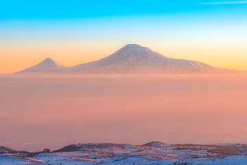 Colorful sunset over the Ararat mountains with mist over Ararat valley at winter as seen from Aragats. Travel destination Armenia