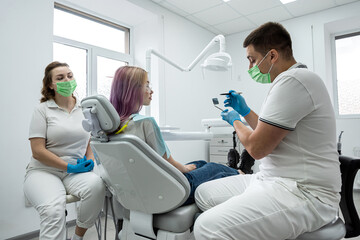 male dentist and a female assistant conduct a consultation for a young girl at the reception.