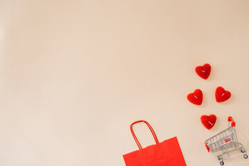Festive composition gift paper red bag, hearts with a shopping basket on a beige background with a place to copy the text. Shopping online for Valentine's Day. Flat lay, top view. - Powered by Adobe